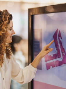 Femme consultant un plan interactif sur une borne tactile