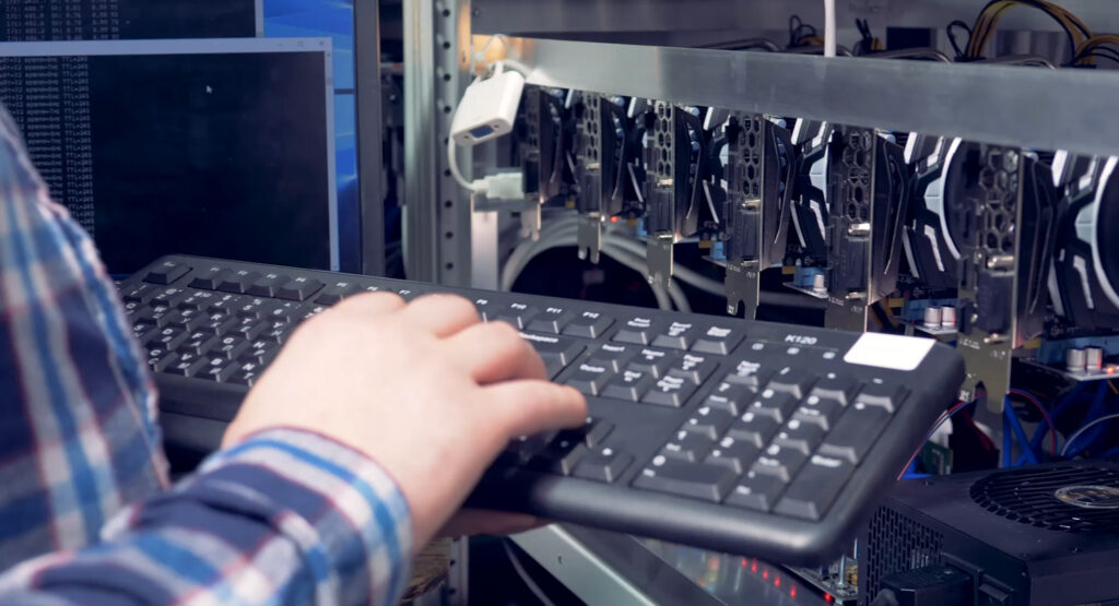 Technicien au clavier devant une baie de cartes graphiques / serveurs