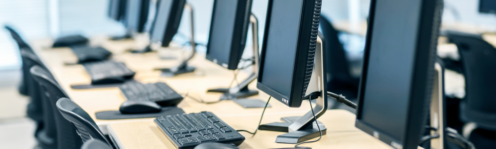 Rangée de postes informatiques avec écrans, claviers et souris